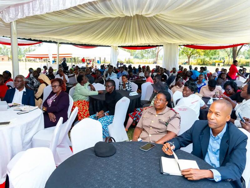 Guests seated at round tables under a white tent, listening during the Phase 2 project launch at Joy Valley Special School