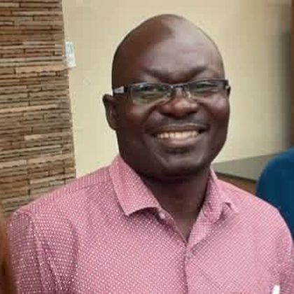 Adrian Sakwa, Chief Executive Officer of DEN, smiling, wearing glasses and a red patterned shirt